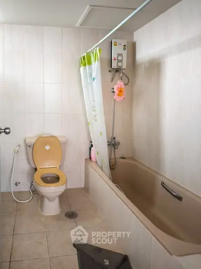 Cozy bathroom with bathtub and shower in a tiled setting.