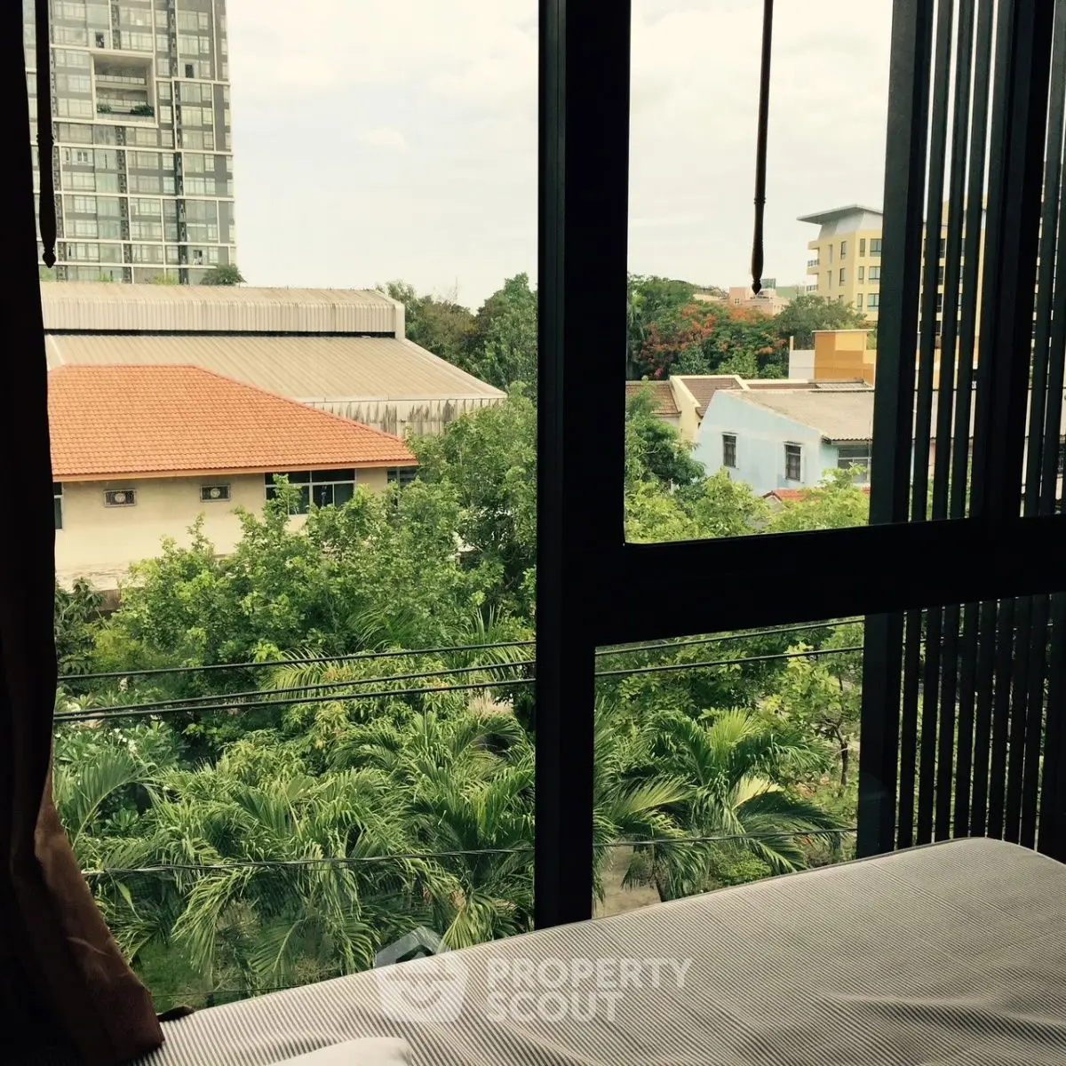 Scenic view from a window overlooking lush greenery and urban buildings.
