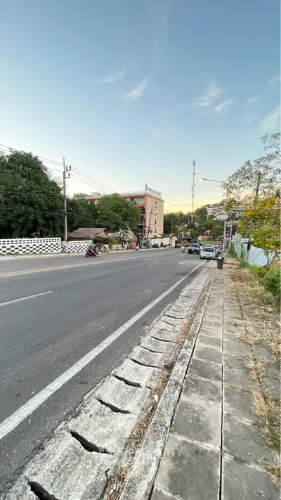 Scenic street view with nearby residential building and lush greenery, ideal for urban living.