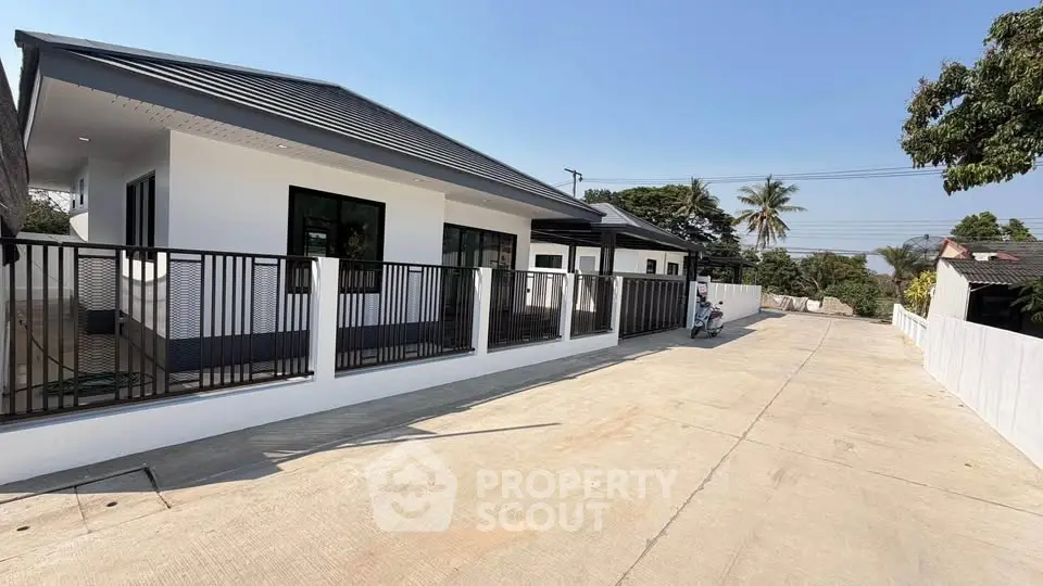 Modern single-story house with sleek design and spacious driveway in a serene neighborhood.