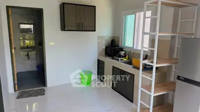 Modern kitchen with sleek cabinetry and open shelving, adjacent to a compact bathroom.