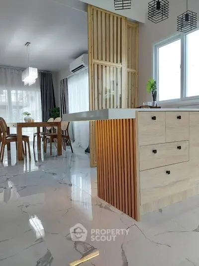Modern kitchen with sleek design and open dining area, featuring marble flooring and wooden accents.