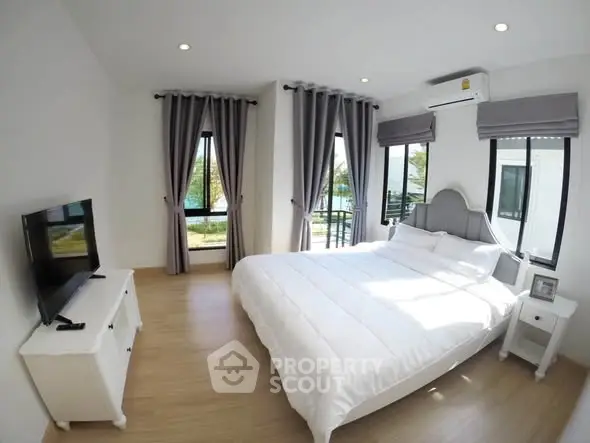Bright and airy bedroom with modern decor and large windows offering scenic views.