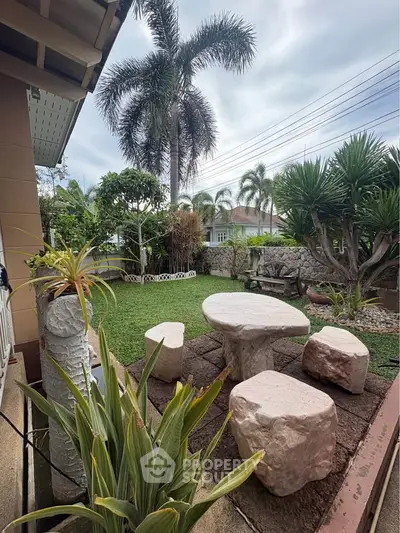 Charming garden with stone seating and lush greenery in a serene residential setting.