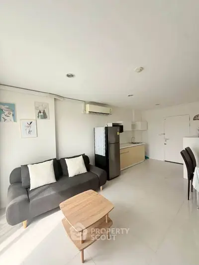 Modern living room with sleek furniture and integrated kitchen in open layout apartment.