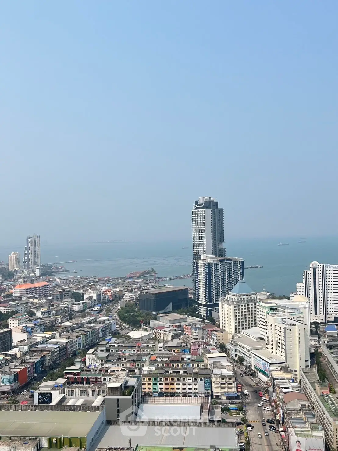 Stunning aerial view of coastal cityscape with high-rise buildings and ocean horizon.
