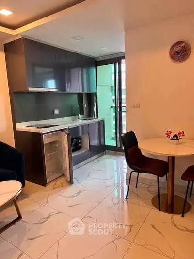 Modern kitchen with sleek cabinetry and dining area in open layout apartment.