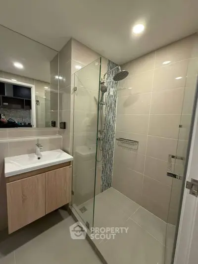 Modern bathroom with glass shower and sleek vanity in contemporary apartment.