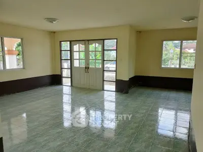 Spacious empty living room with large windows and tiled flooring, perfect for customization.