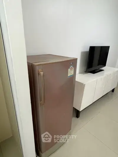 Compact living area with sleek fridge and modern TV setup, perfect for urban living.