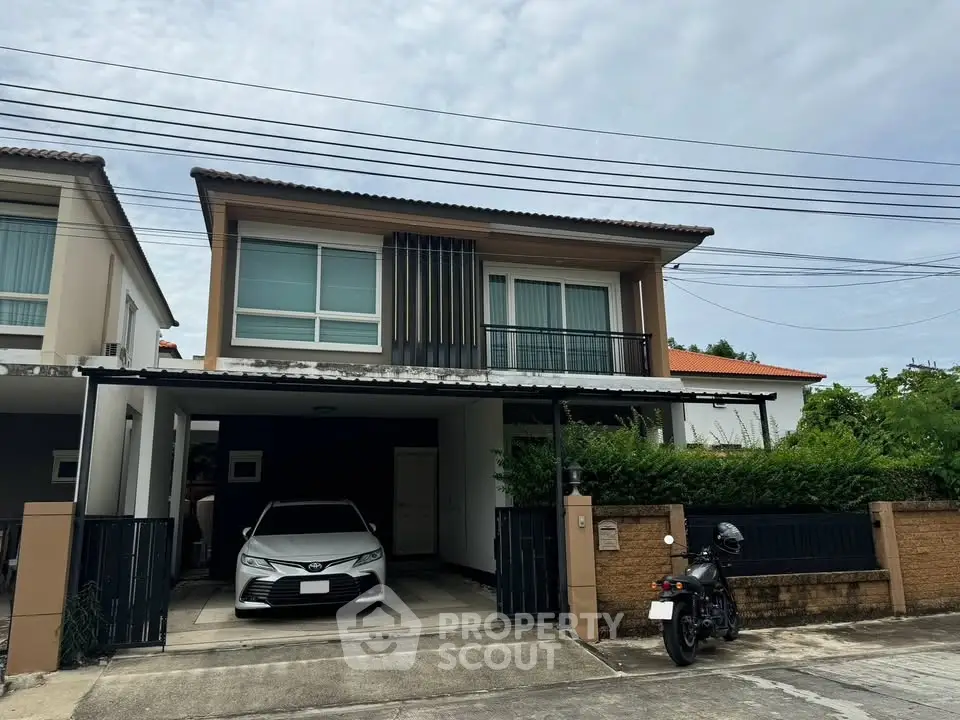 Modern two-story house with carport and motorcycle in driveway, featuring sleek design and lush greenery.