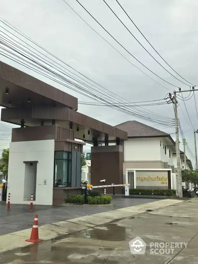 Modern residential building entrance with sleek design and lush landscaping.