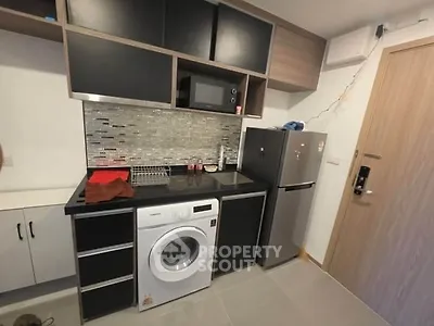 Modern compact kitchen with washing machine and fridge in stylish apartment.
