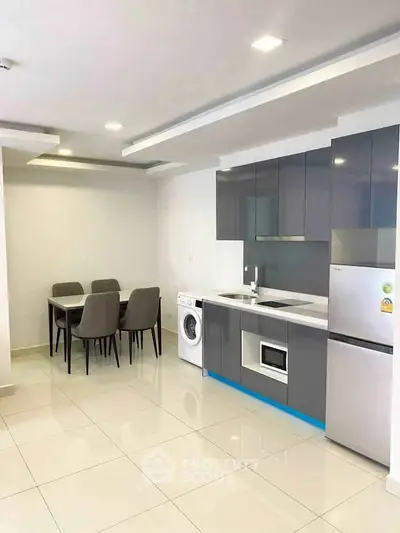 Modern kitchen with sleek cabinetry, dining area, and integrated appliances in a contemporary apartment.