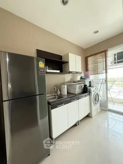 Modern kitchen with stainless steel fridge and washing machine, bright and airy space.