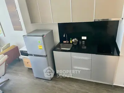 Modern compact kitchen with sleek cabinetry and stainless steel appliances in a stylish apartment.