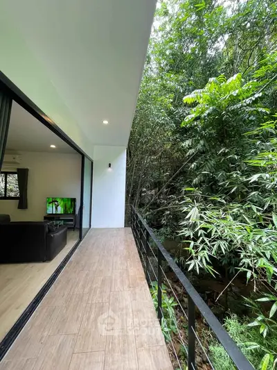 Spacious balcony with lush green view and modern interior glimpse