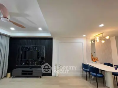 Modern living room with stylish decor and dining area, featuring elegant lighting and sleek furniture.