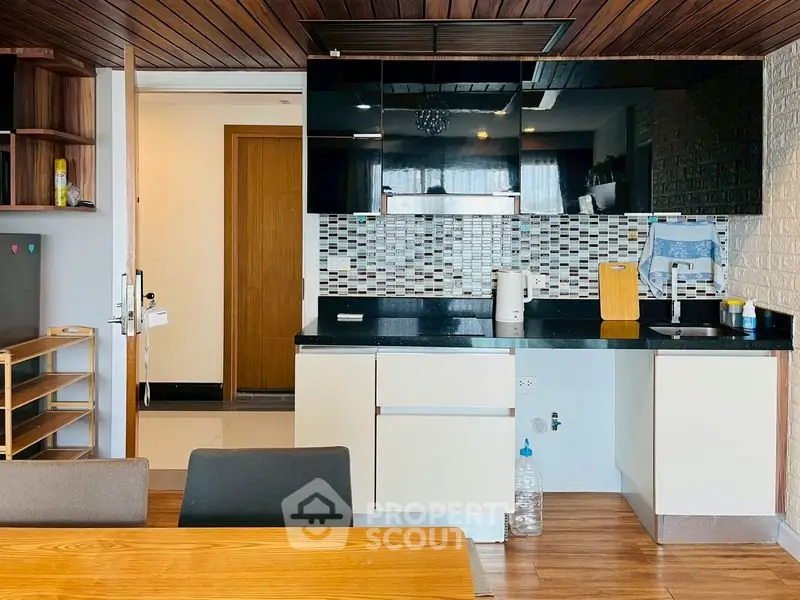 Modern kitchen with sleek cabinetry and stylish backsplash in a contemporary apartment.