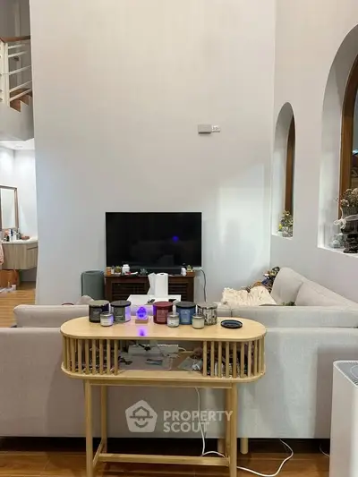 Spacious living room with modern decor and entertainment setup, featuring a cozy sofa and stylish table.