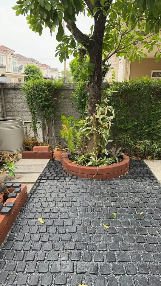Charming garden area with brick planter and lush greenery in a residential setting.