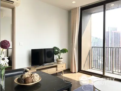 Bright and airy living room with modern furnishings, large windows leading to a balcony with city views, creating a welcoming atmosphere for relaxation and entertainment.