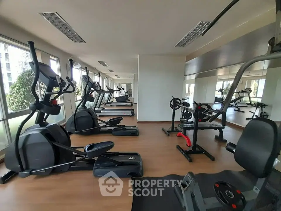 Spacious gym with modern fitness equipment and large mirrors in a residential building.