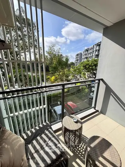 Charming balcony with modern seating and scenic view in urban apartment complex.