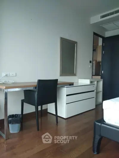 Modern bedroom with sleek desk and chair, hardwood floors, and minimalist decor.