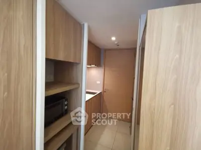 Modern compact kitchen with wooden cabinetry and built-in microwave