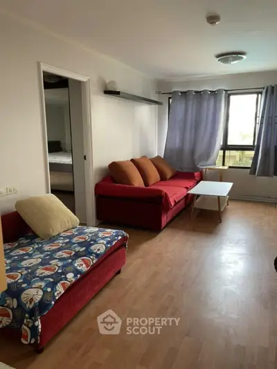 Spacious living room with ample natural light, featuring a cozy red sofa, large windows with curtains, and a versatile open layout perfect for personalization.