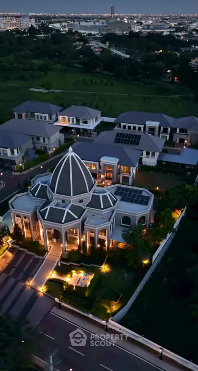 Luxurious mansion with unique dome architecture and landscaped garden, offering stunning aerial view at dusk.