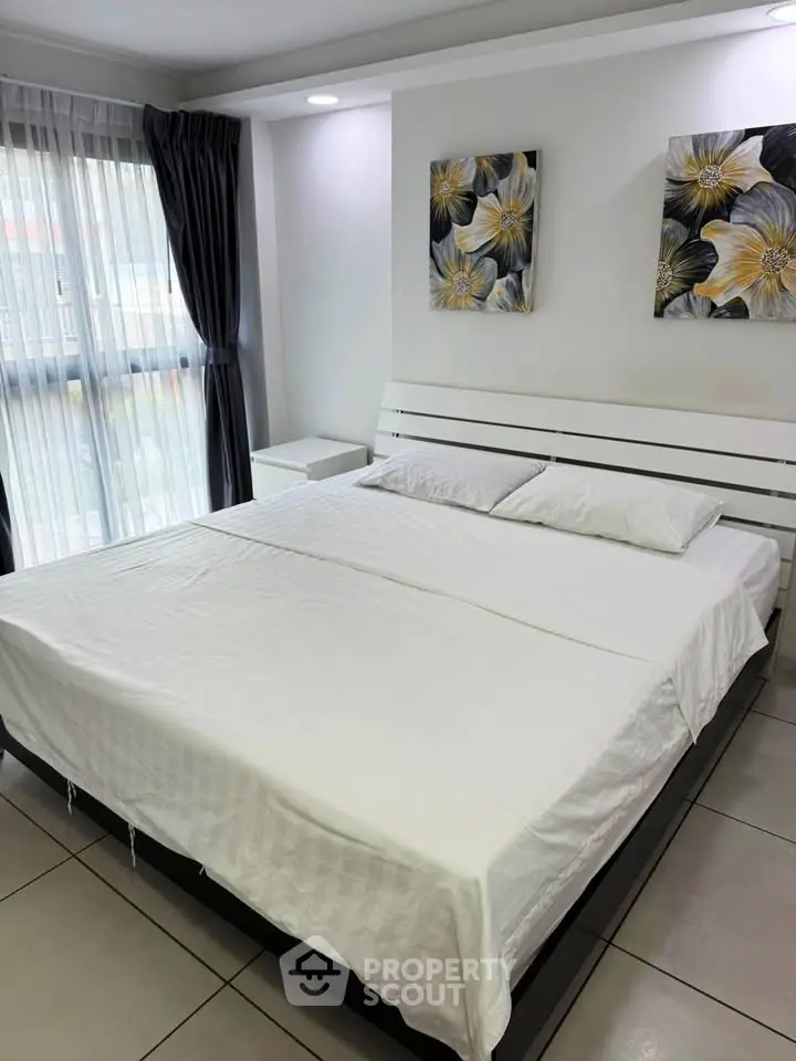 Spacious bedroom with modern decor and large windows for natural light.