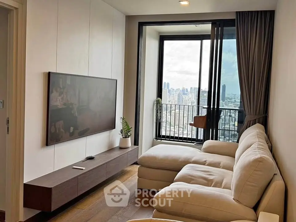 Modern living room with city view, featuring a sleek TV setup and cozy sectional sofa.