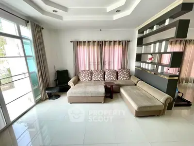 Spacious living room with modern sectional sofa and elegant partition in a bright, airy home.