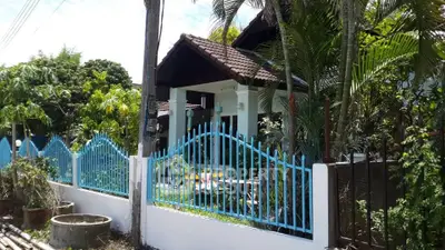 Charming tropical house with blue fence and lush greenery