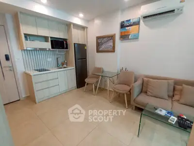 Modern living room with compact kitchen and cozy seating area in a stylish apartment.
