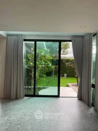 Spacious living room with large glass doors opening to a lush garden, perfect for indoor-outdoor living.