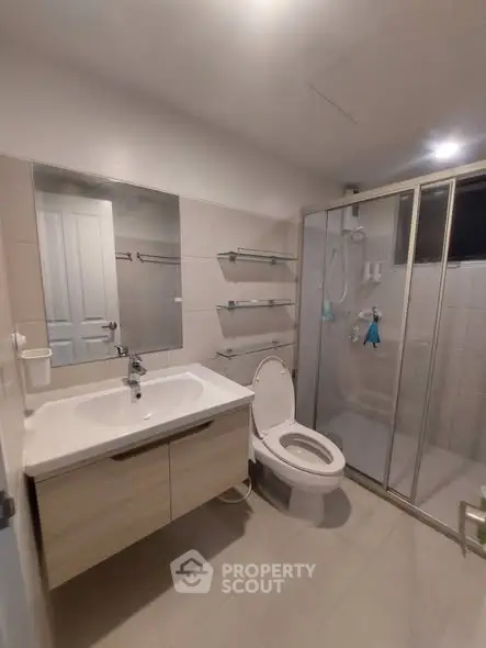 Modern bathroom with glass shower and sleek vanity in contemporary apartment.