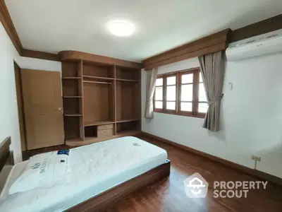 Spacious bedroom with wooden flooring and built-in wardrobe in modern apartment.