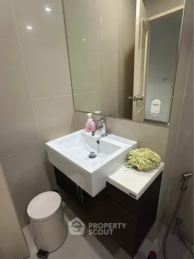 Modern bathroom with sleek sink and mirror, featuring contemporary design and neutral tones.