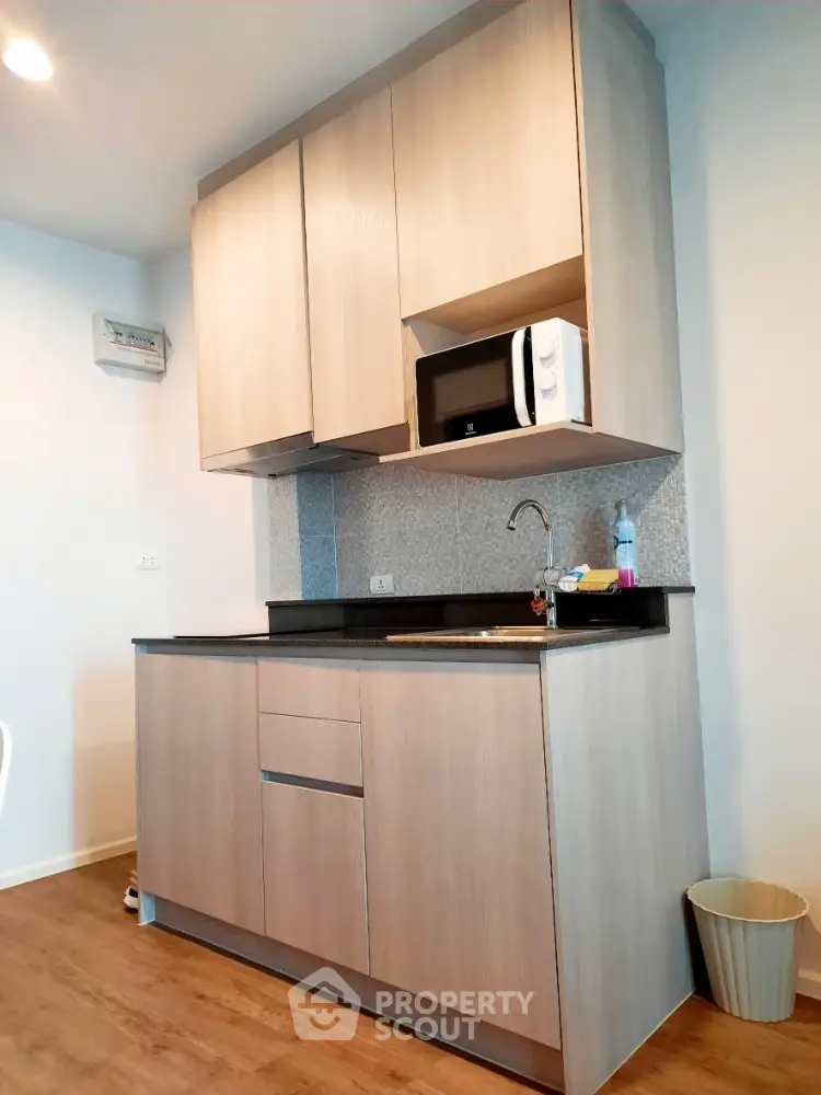 Modern compact kitchen with wooden cabinets and microwave in stylish apartment