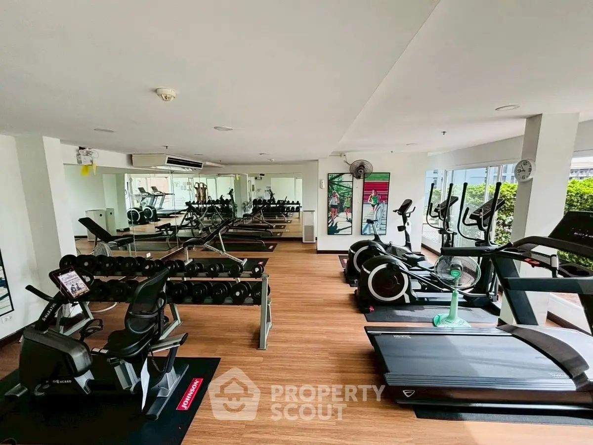 Spacious gym with modern equipment and mirrored walls in a residential building.