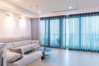 Spacious modern living room with elegant decor and large windows offering natural light.