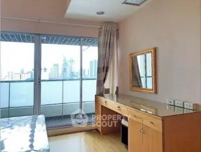 Bright bedroom with city view and balcony access, featuring a wooden desk and mirror.