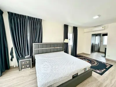 Spacious bedroom with modern decor and large windows for natural light.