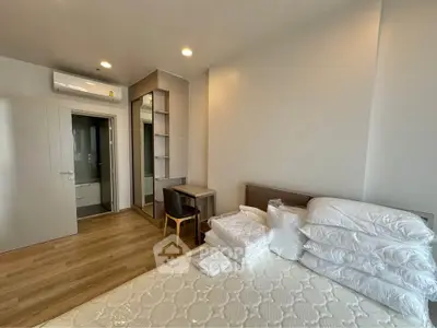 Modern bedroom with wooden flooring, air conditioning, and ample natural light.