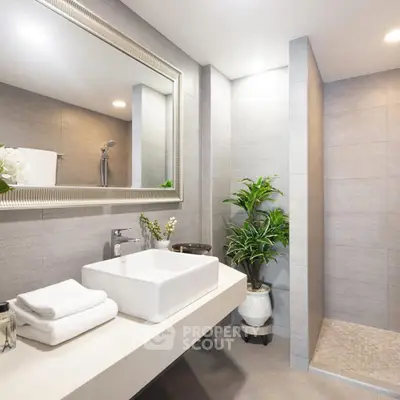 Modern bathroom with sleek design, featuring a spacious walk-in shower and elegant vanity area.