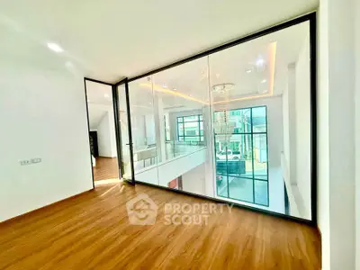 Modern interior with glass walls and wooden flooring, showcasing a spacious and bright living area.