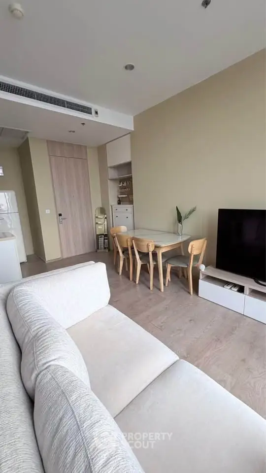 Modern living room with cozy sofa, dining area, and flat-screen TV in a stylish apartment.